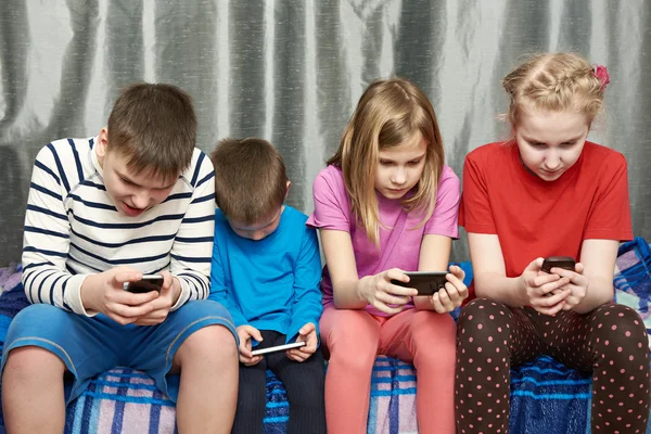 Дети играют в игры на мобильных телефонах — стоковое фото