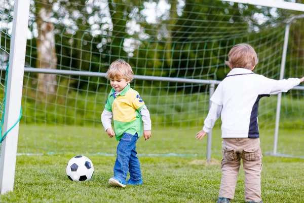 Два маленьких сестру мальчики играют в футбол и футбол — стоковое фото